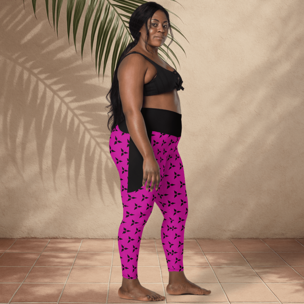 Woman wearing pink leggings with black patterns against a beige wall.