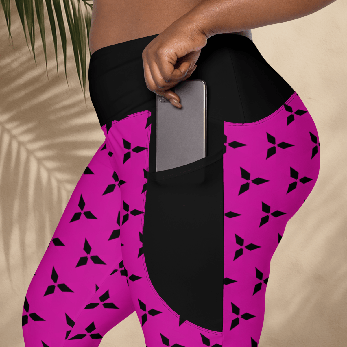 Person wearing pink leggings with black patterns and a pocket, holding a phone.
