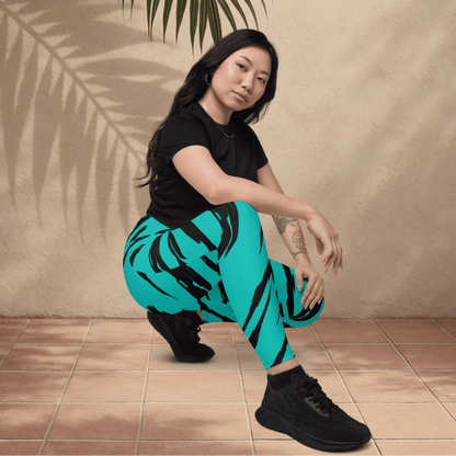 Woman wearing black t-shirt and teal pants with black tiger stripe patterns, sitting on a tiled floor.