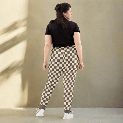 Woman wearing checkered pants and a black top on a neutral background