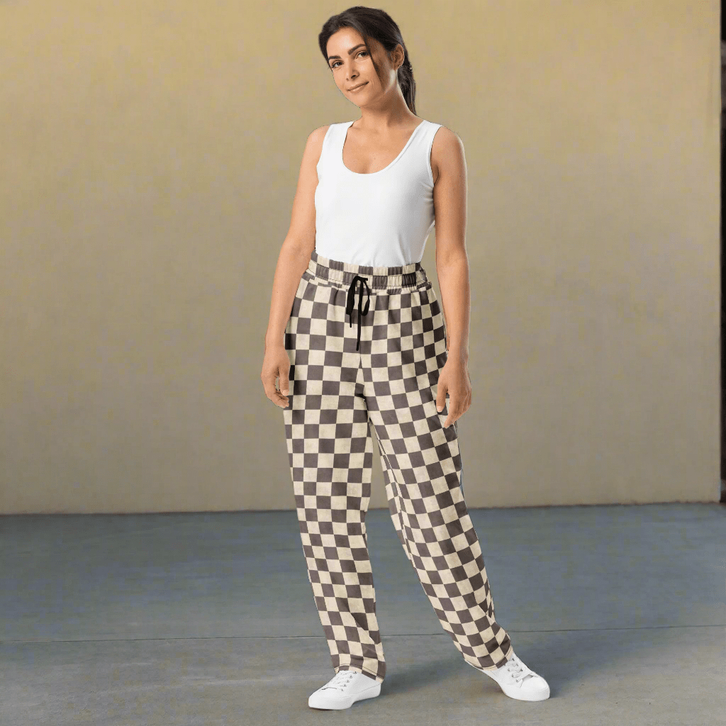 Woman wearing a white sleeveless top and checkered pants against a plain background