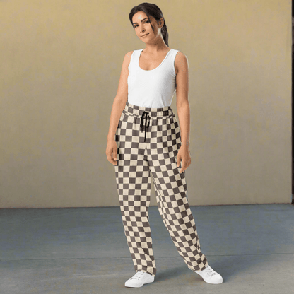 Woman wearing a white sleeveless top and checkered pants against a plain background