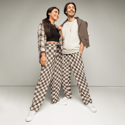 Two people wearing matching checkered pants against a plain background