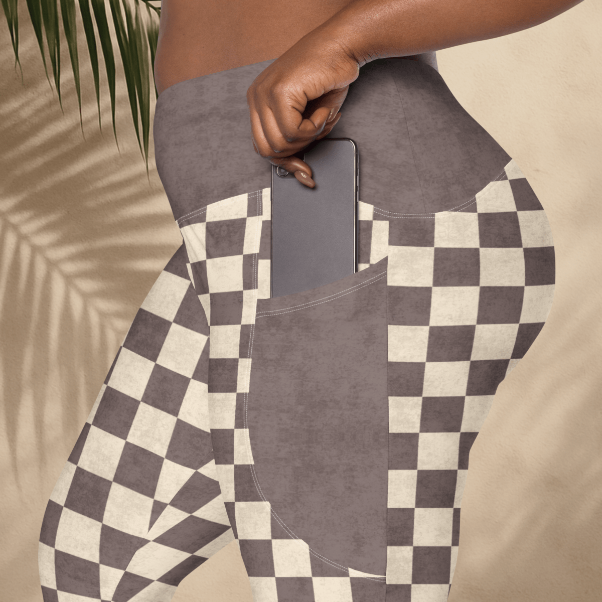 Person wearing checkered pants with a pocket holding a phone, against a neutral background.