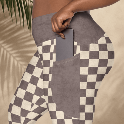 Person wearing checkered pants with a pocket holding a phone, against a neutral background.