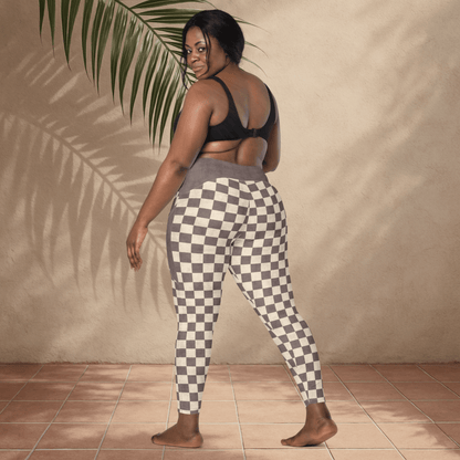 Woman wearing checkered pants and a black top against a beige wall.