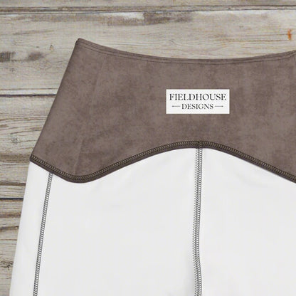 Close-up of a brown garment with 'Fieldhouse Designs' label on a wood background