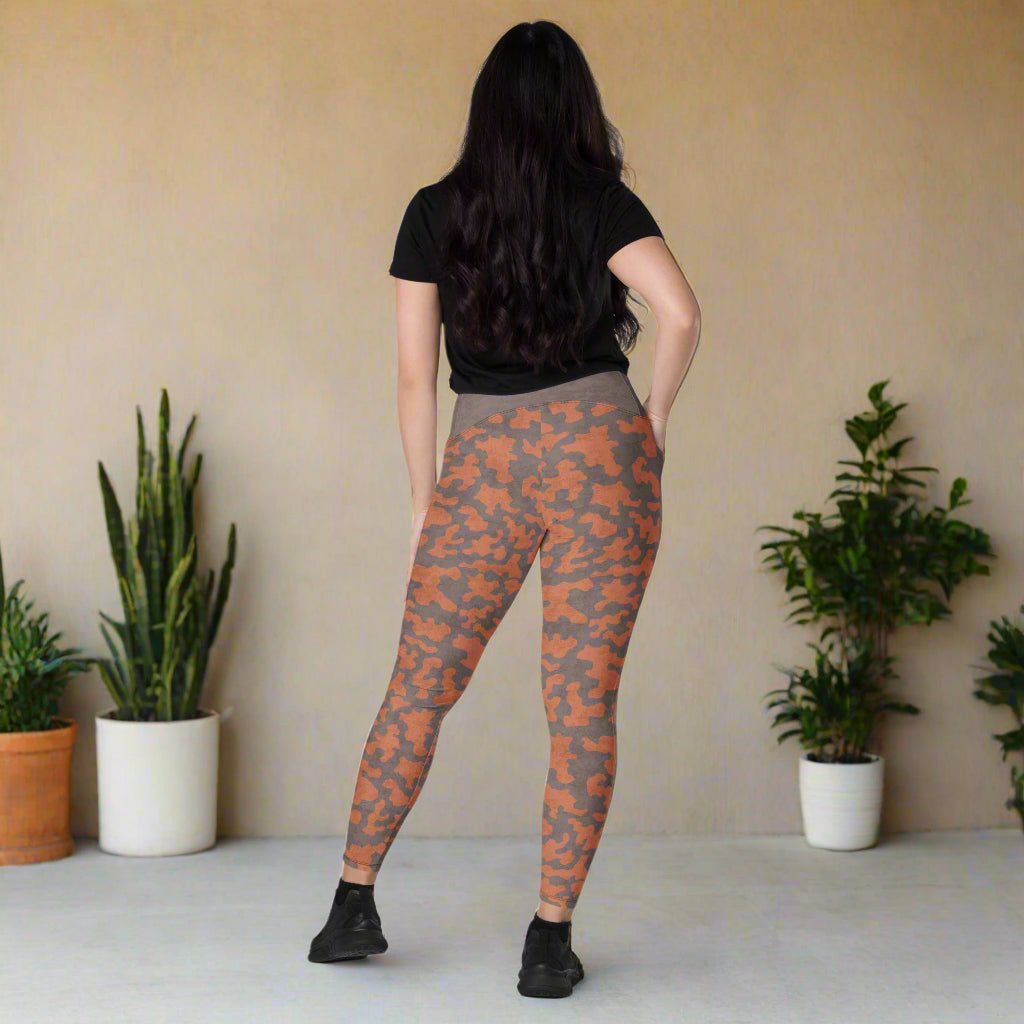Person wearing camouflage leggings and a black top on a neutral background