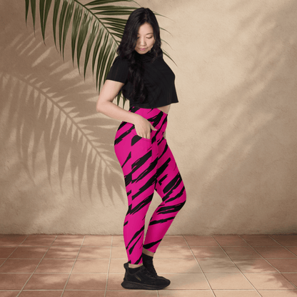 Woman wearing pink and black tiger striped leggings against a beige wall.