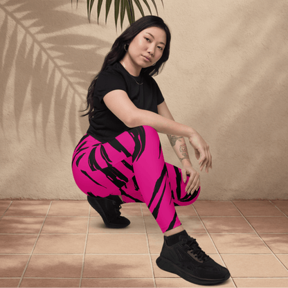 Woman wearing pink pants with black tiger stripe patterns and a black top, sitting on a tiled floor.
