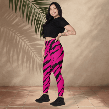 Woman wearing pink and black tiger striped leggings against a beige wall.