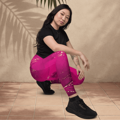 Woman wearing pink leggings and black top sitting on a tiled floor with a beige wall and plant leaf in the background.