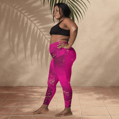 Woman wearing a black sports bra and pink leggings standing against a beige wall with a plant.