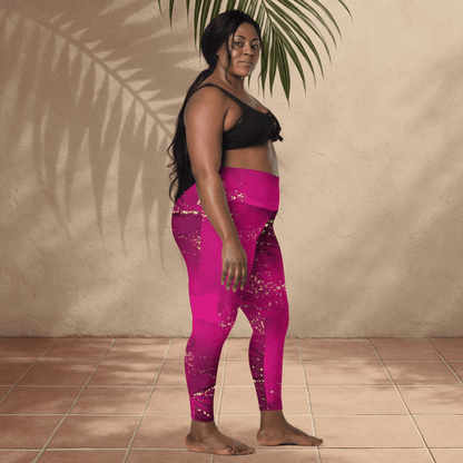 Woman wearing pink leggings and black sports bra standing against a beige wall.