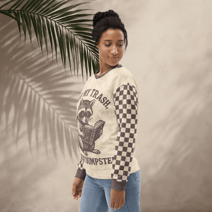 model wearing Beige crewneck sweatshirt with espresso checkered sleeves. Featuring a raccoon reading a book graphic and text 'Not my trash, not my dumpster' 