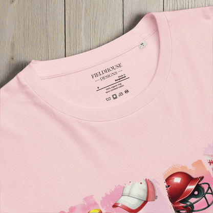 Pink t-shirt with 'Fieldhouse Designs' label and sports equipment graphics on a wooden surface