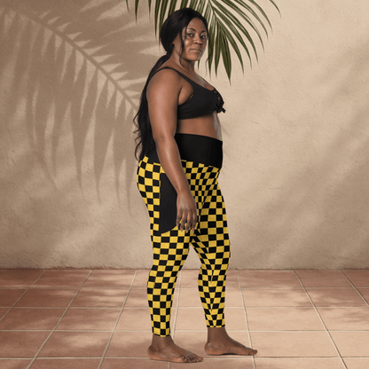 Woman wearing black and yellow checkered pants standing against a beige wall.