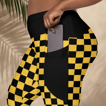 Person wearing black and yellow checkered pants with a phone in the pocket against a beige background.