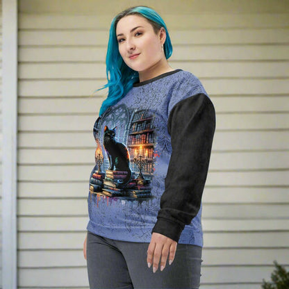Person wearing a blue and black sweater with a cat and book design on a white background