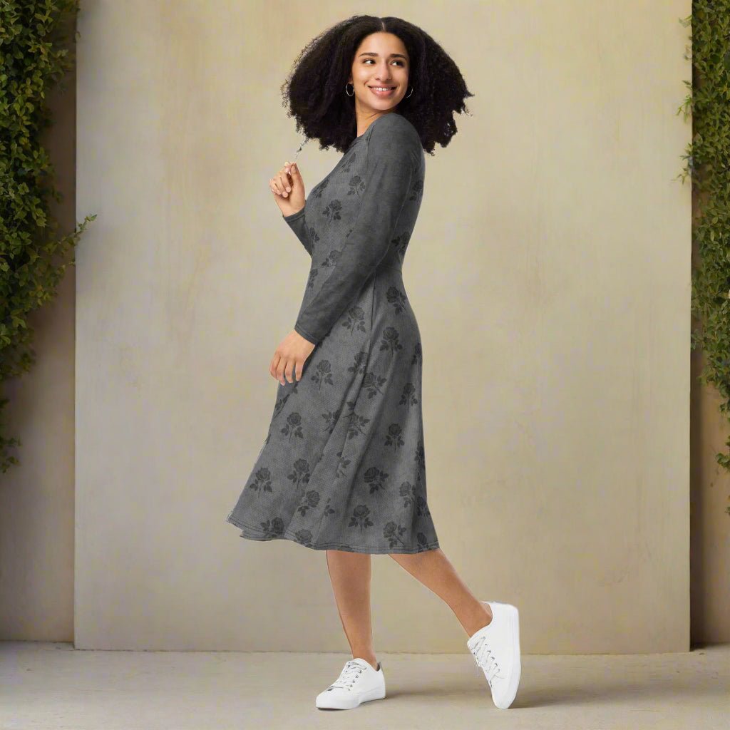 Woman wearing a gray floral dress with white sneakers against a beige wall.