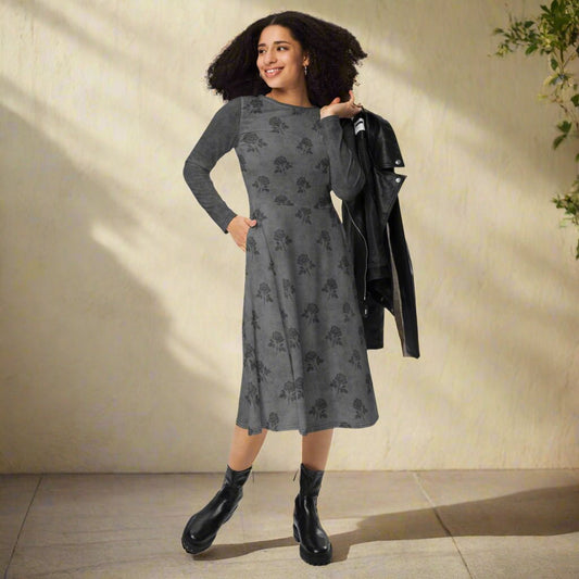 Woman wearing a gray patterned dress with black boots against a beige wall.