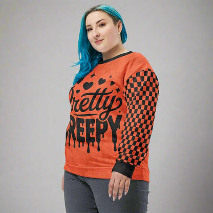Person wearing an orange sweatshirt with black text and checkered sleeves on a neutral background