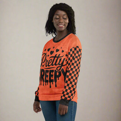 Person wearing an orange sweater with black text and checkered pattern on a plain background