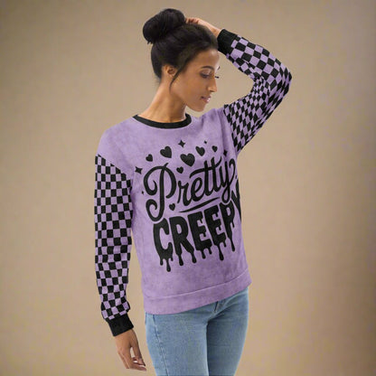 Woman wearing a purple sweater with 'Pretty Creepy' text and checkered sleeves on a beige background