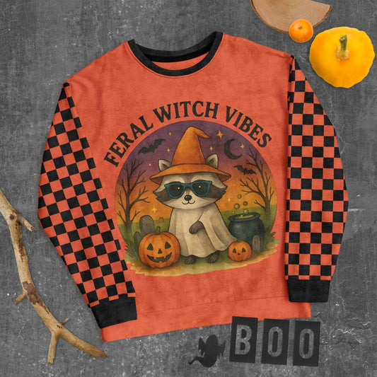 Halloween-themed sweatshirt with raccoon graphic and 'Feral Witch Vibes' text on a checkered background.