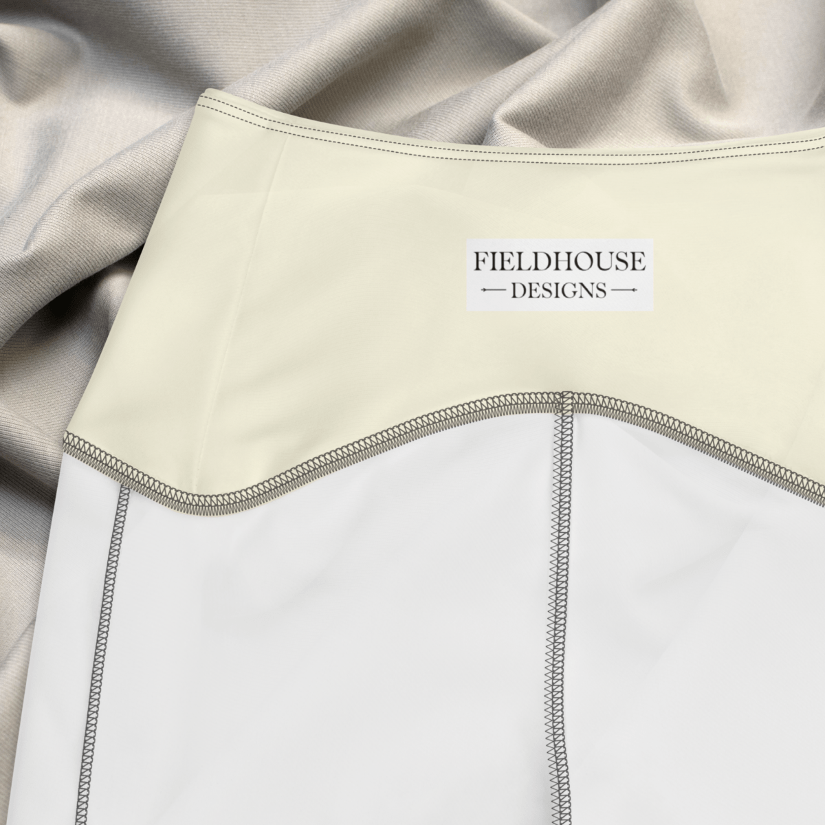 Close-up of a garment with 'Fieldhouse Designs' label, featuring beige and white colors.