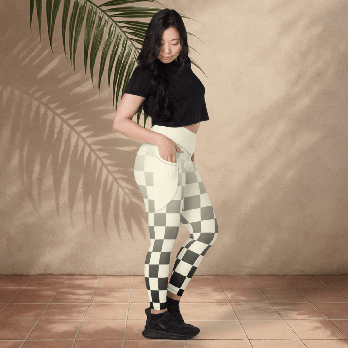 Woman wearing black and ivory checkered pants against a beige wall.