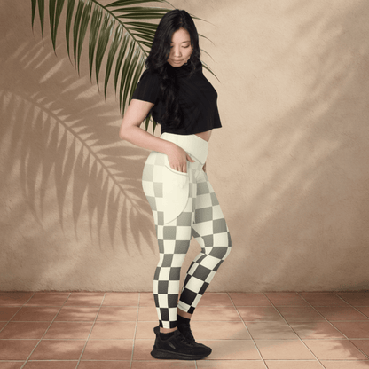 Woman wearing black and ivory checkered pants against a beige wall.