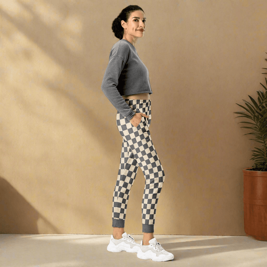 Woman wearing a gray cropped sweatshirt and checkered leggings on a neutral background