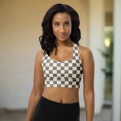 Woman wearing a checkered sports bra and black leggings on a neutral background