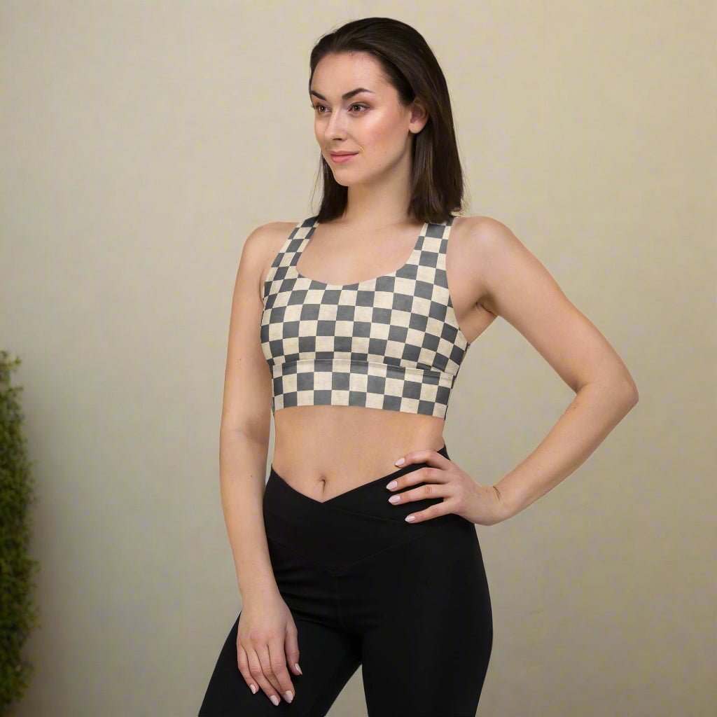 Woman wearing a checkered sports bra and black leggings against a plain background
