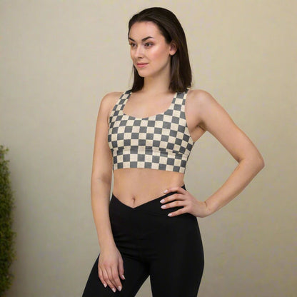 Woman wearing a checkered sports bra and black leggings against a plain background