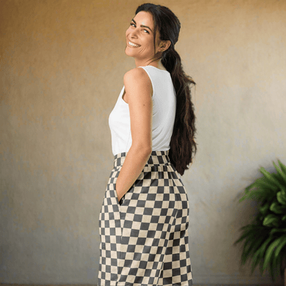 Woman wearing a white sleeveless top and checkered pants on a neutral background
