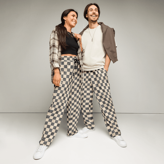 Two people wearing matching checkered pants against a plain background