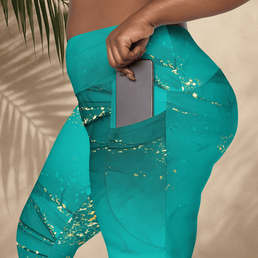 Teal leggings with gold glitter pattern worn by a person, held against a neutral background.