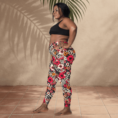 Woman wearing a black sports bra and colorful floral leggings standing against a beige wall.