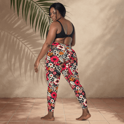 Woman wearing colorful floral and animal print pants against a beige wall.