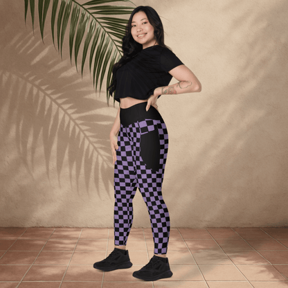 Woman wearing black and purple checkered leggings with a black crop top against a beige wall.