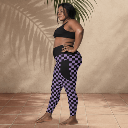 Woman wearing a black sports bra and purple checkered leggings against a beige wall.