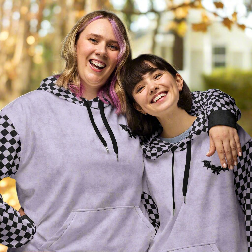 Two people wearing matching lavender hoodies with checkered sleeves in an outdoor setting.