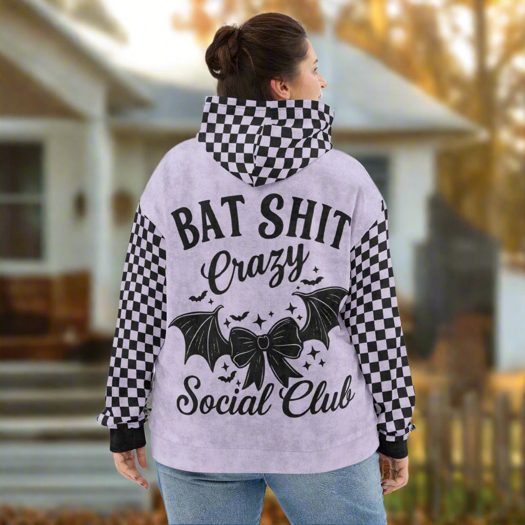 Person wearing a hoodie with text and bat design outdoors