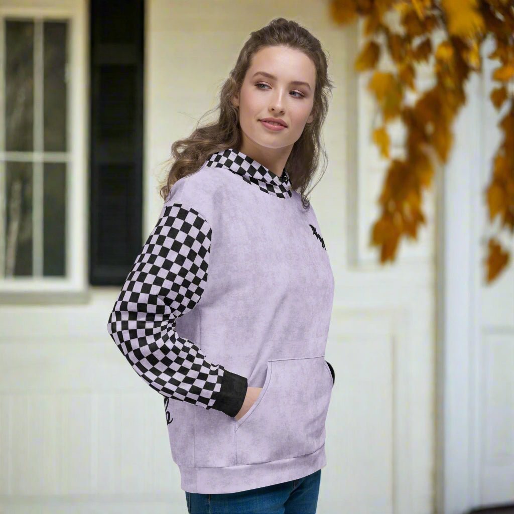 Woman wearing a light purple hoodie with checkered sleeves standing outdoors.