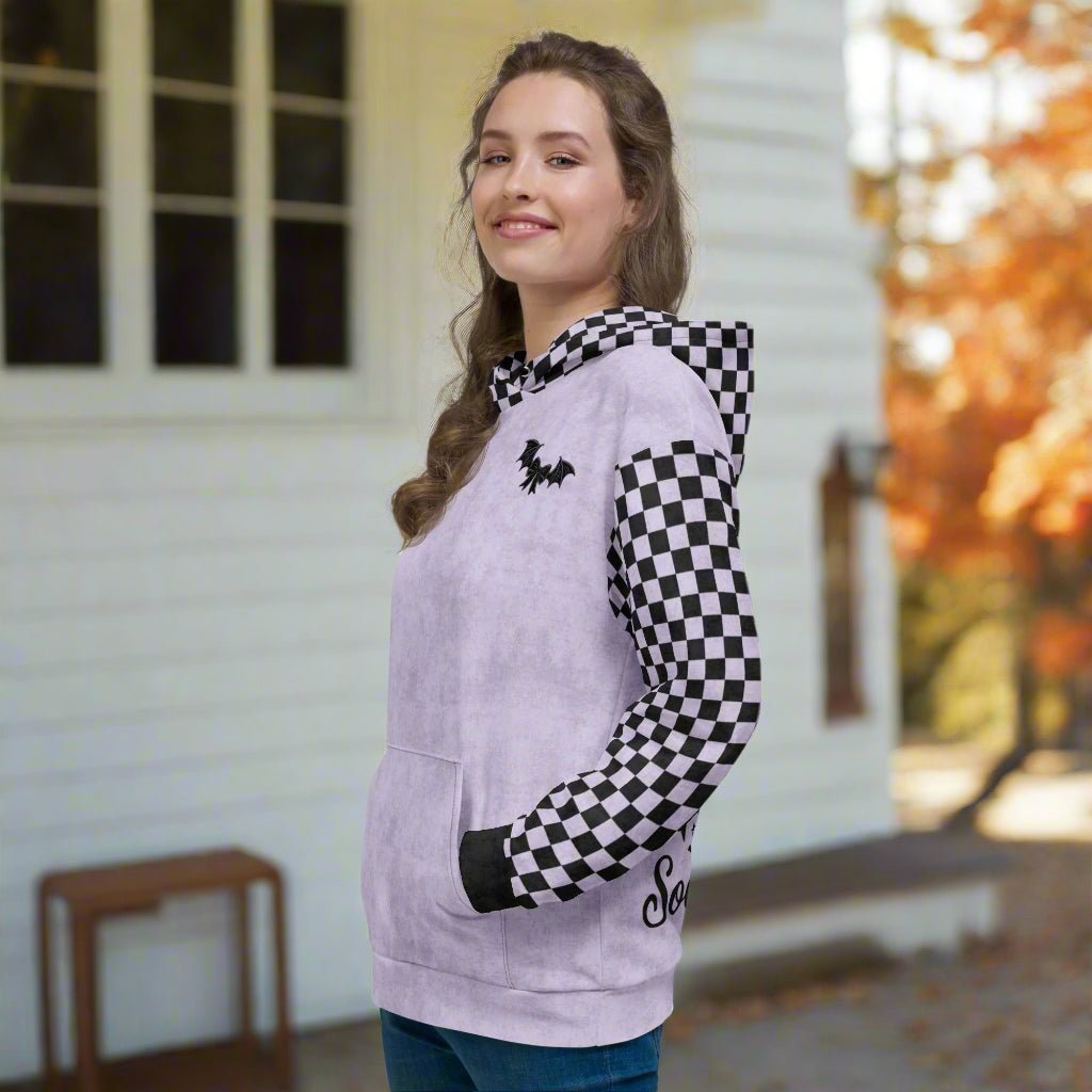 Woman wearing a checkered sleeve hoodie with a logo, standing outdoors.