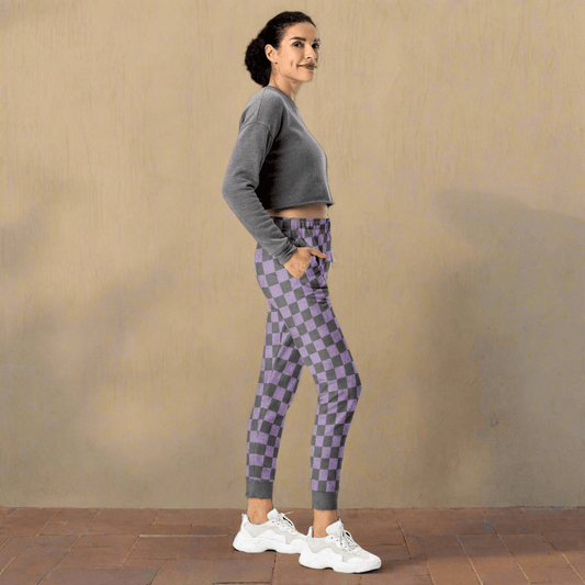 Woman wearing gray and purple checkered pants on a neutral background