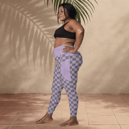 Woman wearing a black sports bra and purple checkered leggings standing against a beige wall.