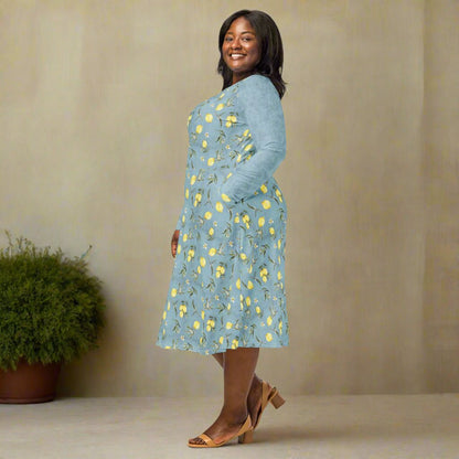 Woman wearing a blue floral dress standing against a beige wall with a plant in the background.